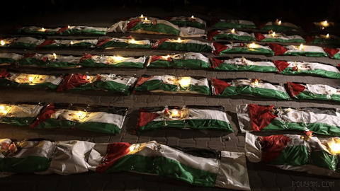 Bodies of Palestinians, wrapped in shrouds and Palestinian flags, await
