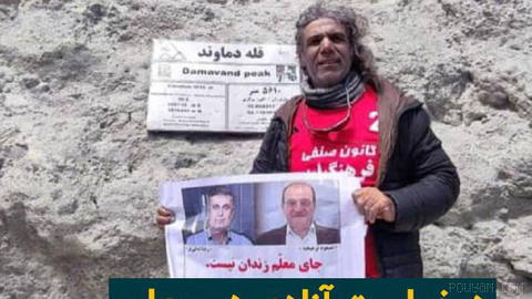 Ali Haji, a teachers’ union activist, mountaineer, and environmental campaigner, after reaching the Damavand summit while holding a photo of Abdolreza Amani…